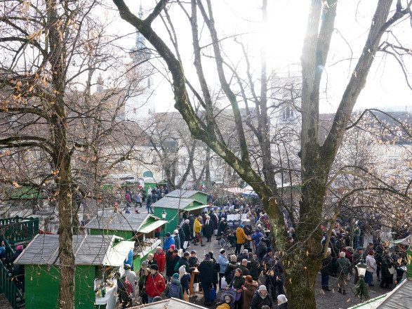 Blick von schräg oben auf mehrere kleine Holzhütten mit vielen Menschen davor.