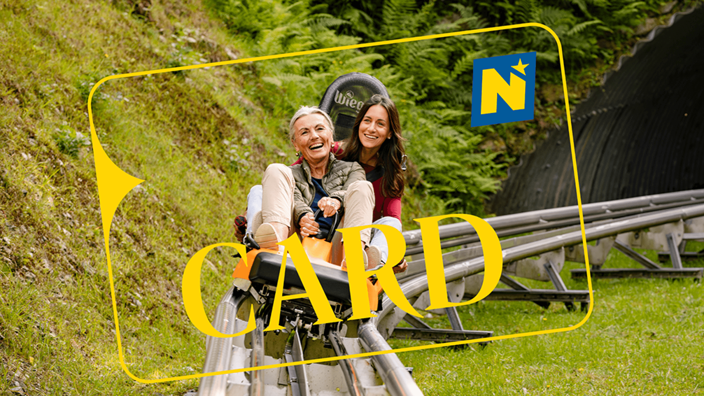 Zwei Frauen fahren mit der Sommerrodelbahn und haben Spaß dabei