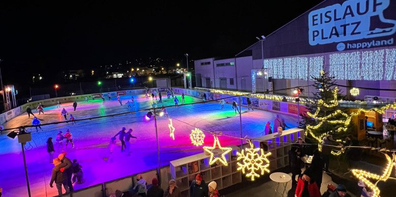 Bunt beleuchteter Eislaufplatz auf dem Menschen eislaufen.