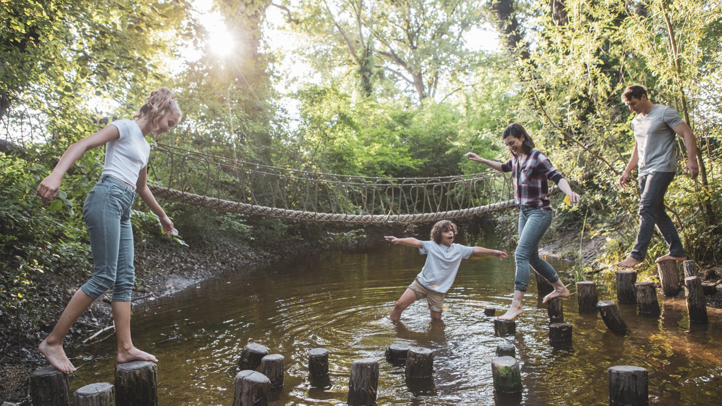 Familie die über Holzpflöcke im Wasser geht
