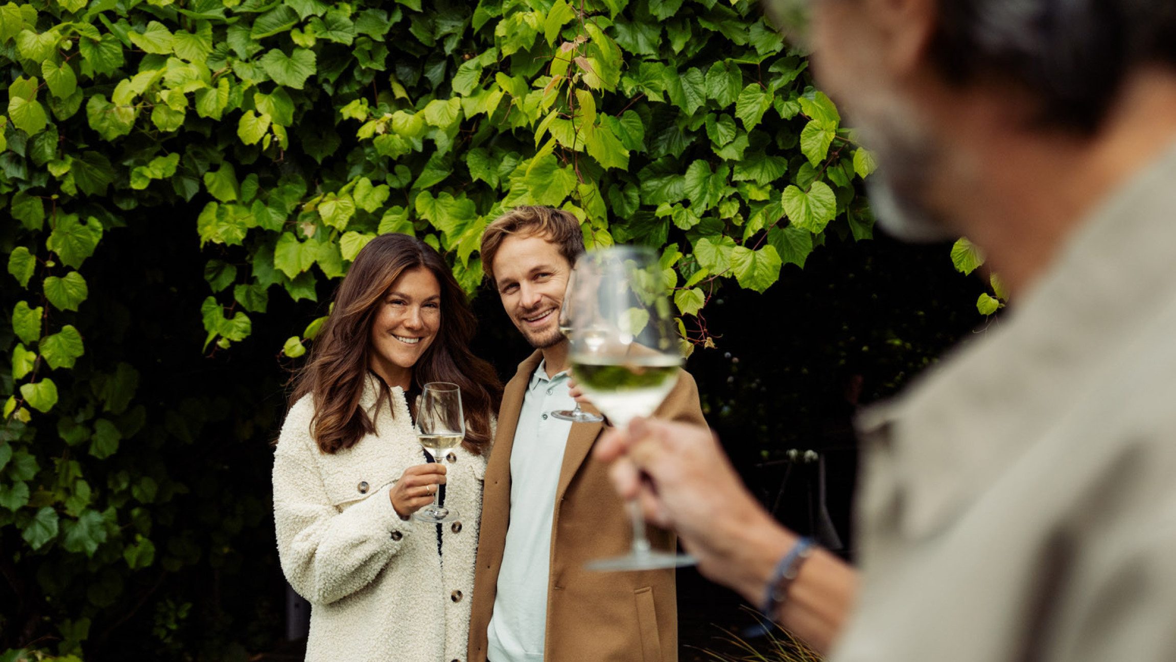 Zwei Erwachsene die mit einem Glas Wein anstoßen