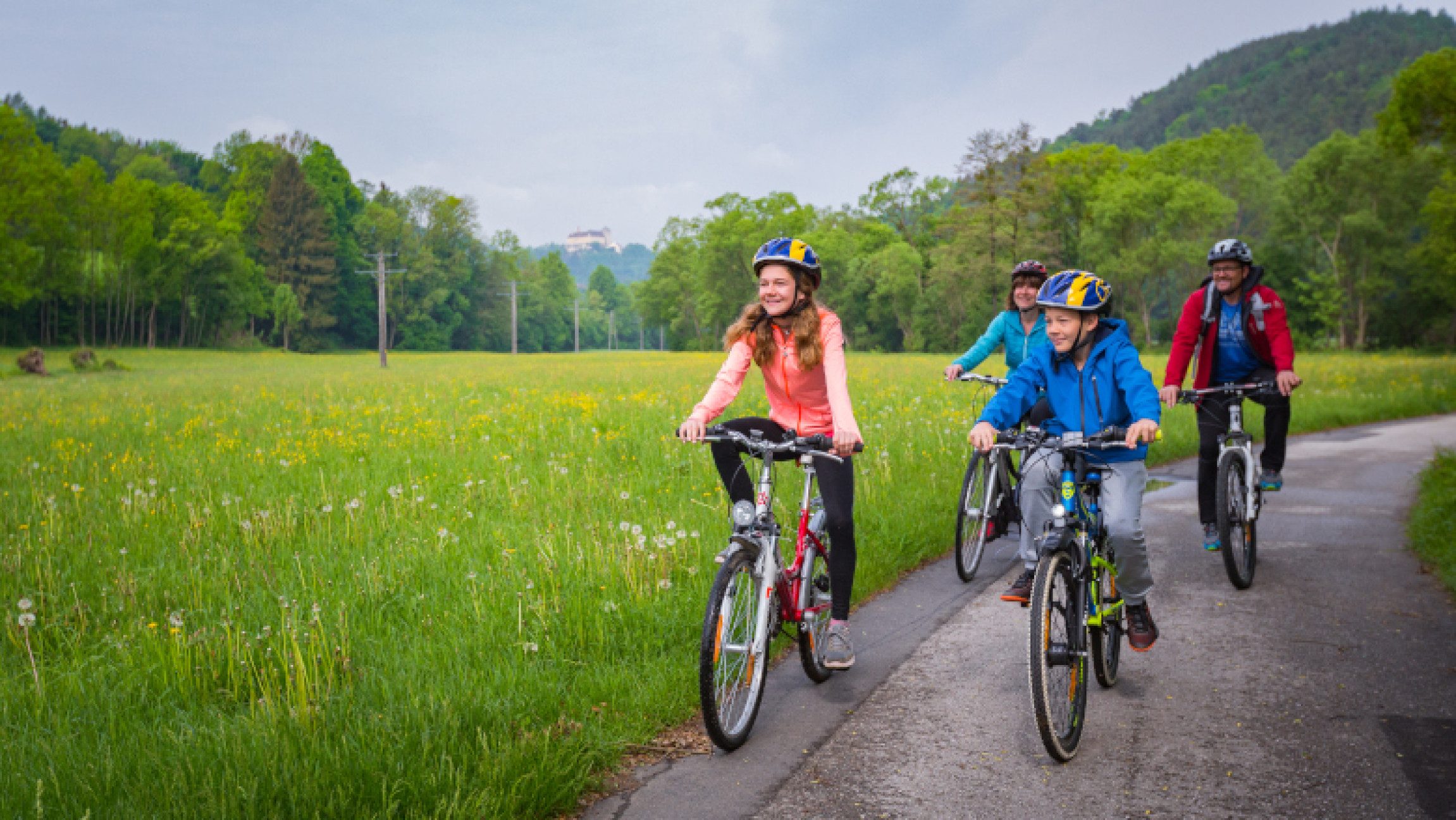Familie beim Radfahren neben Wiese