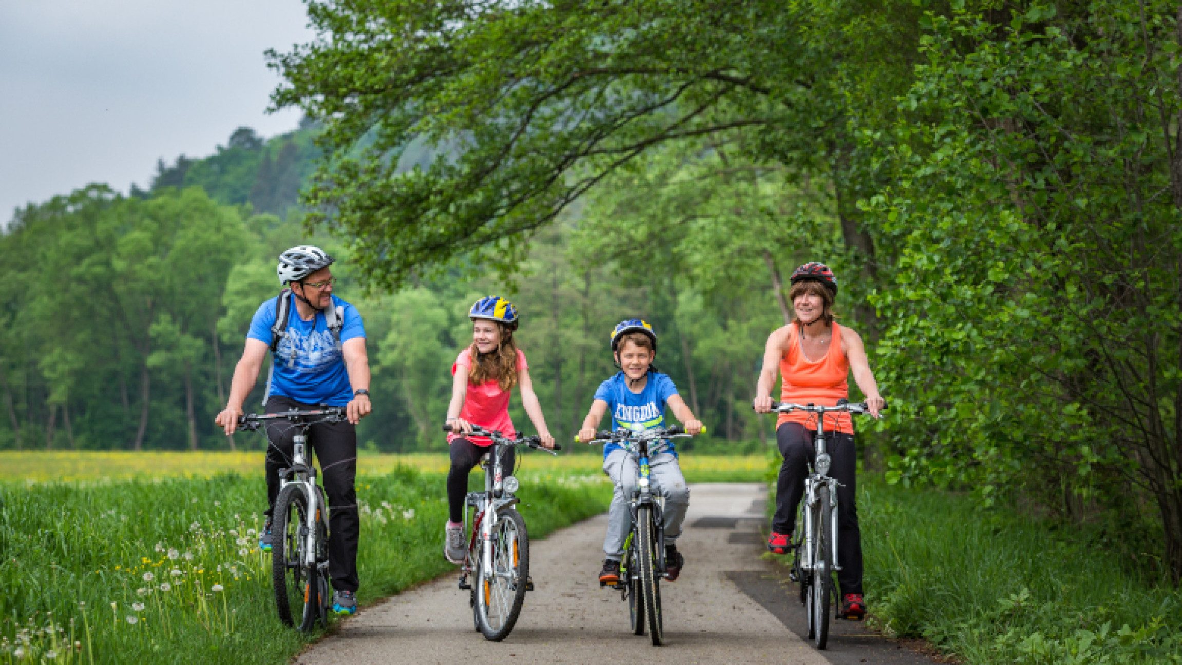 Familie beim Radfahren neben einem Wald