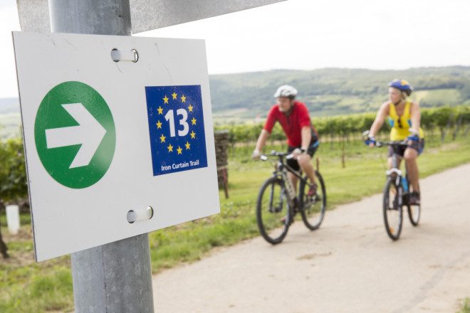 Beschilderung und Radfahrer:innen am Iron Curtain Trail