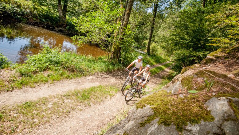 Zwei Radfahrer:innen am KTM-Radweg neben Wackelsteinen im Waldviertel
